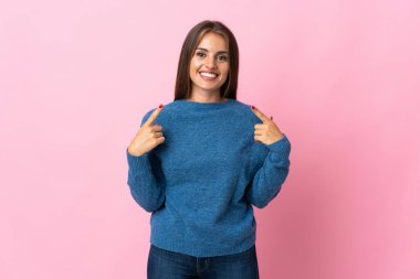 Pembe arka planda izole edilmiş genç Uruguaylı kadın baş parmak işareti yapıyor.