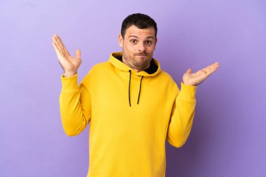 İzole edilmiş mor arka planı olan Brezilyalı adam şüpheli hareketler yapıyor.