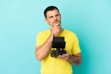 Brezilyalı bir adam uzaktan kumandayla izole edilmiş mavi arkaplanı kontrol ediyor.