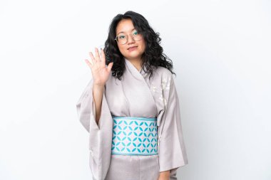 Kimono giyen genç Asyalı kadın beyaz arka planda izole edilmiş, parmaklarıyla beşi sayıyor.