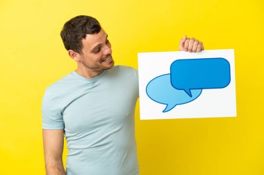 İzole edilmiş mor arkaplan üzerinde Brezilyalı bir adam elinde konuşma balonu simgesi olan bir levha tutuyor.