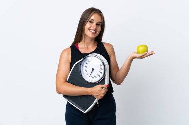 Genç Uruguaylı kadın tartı makinesi ve elmasıyla beyaz arka planda izole edilmiş.