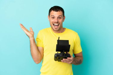 Brezilyalı adam uzaktan kumandalı İHA ile izole edilmiş mavi arka plan üzerinde şok olmuş yüz ifadesini tutuyor.