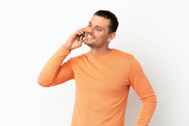 İzole edilmiş beyaz arka planda Brezilyalı bir adam cep telefonuyla sohbet ediyor.