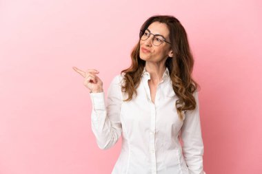 Pembe arka planda izole edilmiş orta yaşlı beyaz kadın çözümü bulmak için parmağını kaldırıyor.