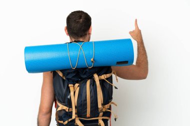 Brezilya 'lı dağcı büyük bir sırt çantası ile izole edilmiş beyaz arka plan üzerinde işaret parmağı ile