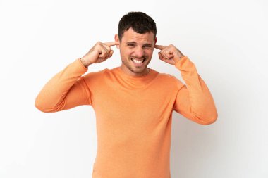 Brezilyalı adam izole edilmiş beyaz arka planda hayal kırıklığına uğramış ve kulaklarını kapatmış.