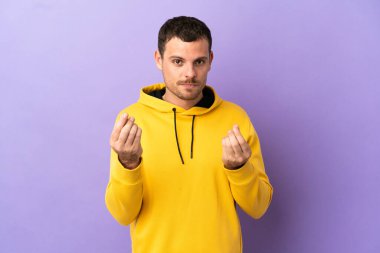 İzole edilmiş mor arka planı olan Brezilyalı adam para jesti yapıyor ama mahvoldu.