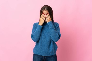 Genç Uruguaylı kadın pembe arka planda izole edilmiş, yorgun ve hasta bir ifadeyle.