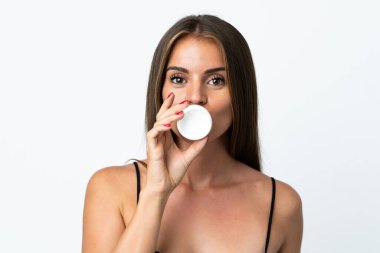 Genç Uruguaylı kadın, beyaz arka planda nemlendirici ile izole edilmiş.