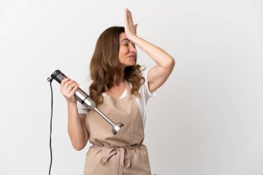 Beyaz arka planda izole edilmiş el blenderi kullanan orta yaşlı beyaz kadın bir şey fark etti ve çözüme niyetlendi.