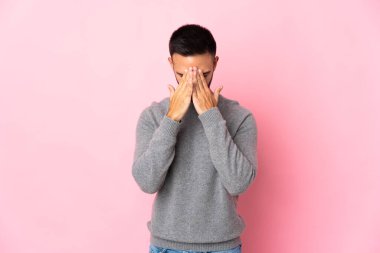 Pembe arka planda izole edilmiş, yorgun ve hasta bir ifadeyle genç beyaz bir adam.