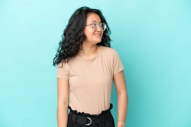 Asyalı genç bir kadın mavi arka planda izole edilmiş.