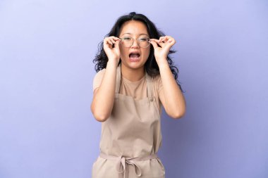 Restoran Asyalı garson mor arka planda gözlüklü ve şaşırmış.