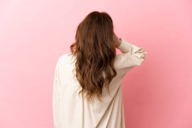 Orta yaşlı beyaz kadın pembe arka planda izole edilmiş ve düşünüyor.