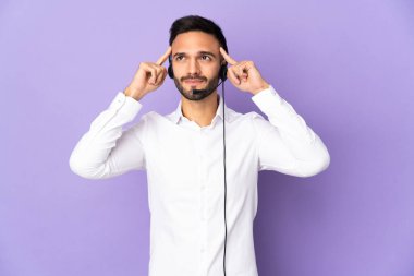 Mor arka planda izole edilmiş bir kulaklıkla çalışan pazarlamacı adamın şüpheleri ve düşünceleri var.