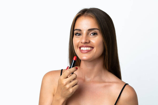 Young Uruguayan woman isolated on white background holding red lipstick