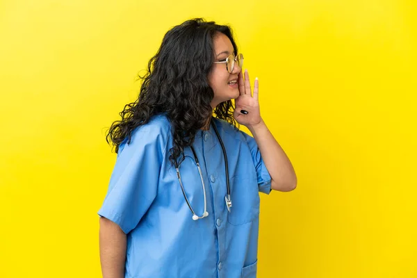 年轻的外科医生亚洲妇女 在黄色背景下被隔离 嘴巴张开 侧向外张大 — 图库照片