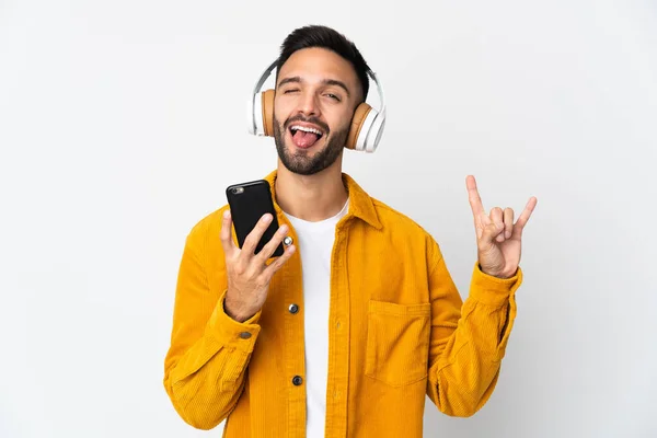 Joven Caucásico Aislado Sobre Fondo Blanco Escuchando Música Con Móvil —  Fotos de Stock