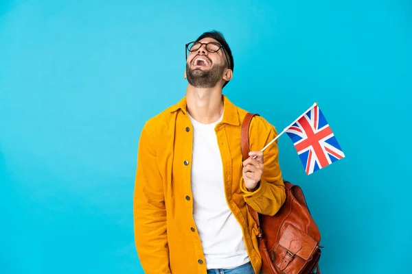 年轻的高加索男子举着一面英国国旗 被黄色背景的笑声隔开 — 图库照片