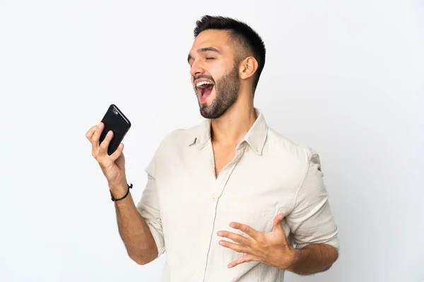 Young Caucasian Man Isolated White Background Using Mobile Phone Singing — Stock Photo, Image