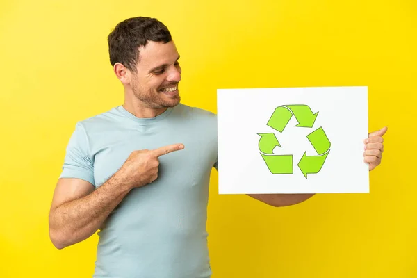 Brazylijczyk Odizolowanym Fioletowym Tle Trzymający Tabliczkę Ikoną Recyklingu Wskazujący — Zdjęcie stockowe
