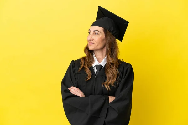 Middle aged university graduate isolated on yellow background happy and smiling