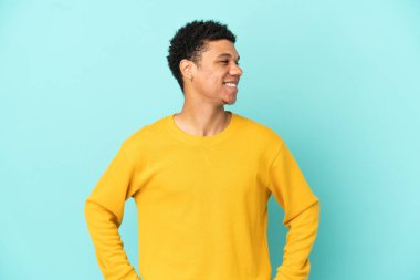 Young African American man isolated on blue background looking side