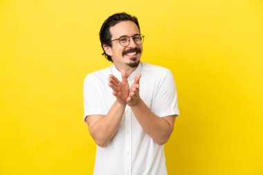 Sarı arka planda izole edilmiş genç beyaz adam bir konferanstan sonra alkışlıyor.