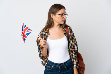 Young Lithuanian woman holding an United Kingdom flag isolated on white background looking to the side
