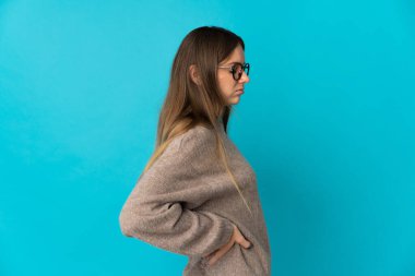 Genç Litvanyalı bir kadın mavi arka planda izole edilmiş, çaba gösterdiği için sırt ağrısı çekiyor.