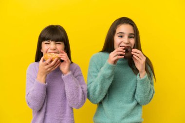 İzole edilmiş arka planda donut tutan kız kardeşler