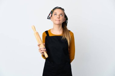 Young Lithuanian woman holding a rolling pin isolated on white background and looking up