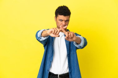 Young African American man isolated on yellow background making stop gesture with her hand to stop an act