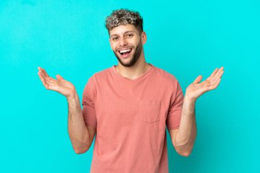 Mavi arka planda izole edilmiş yakışıklı, beyaz bir adam. Gülümsüyor.