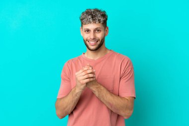 Mavi arka planda izole edilmiş yakışıklı beyaz adam gülüyor.