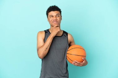Basketball player African American man isolated on blue background and looking up
