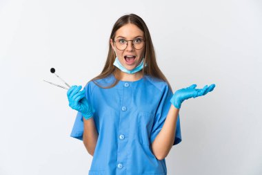Lithuanian woman dentist holding tools over isolated background with shocked facial expression