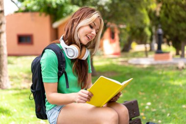 Dışarıda elinde bir defter tutan genç bir kız öğrenci.