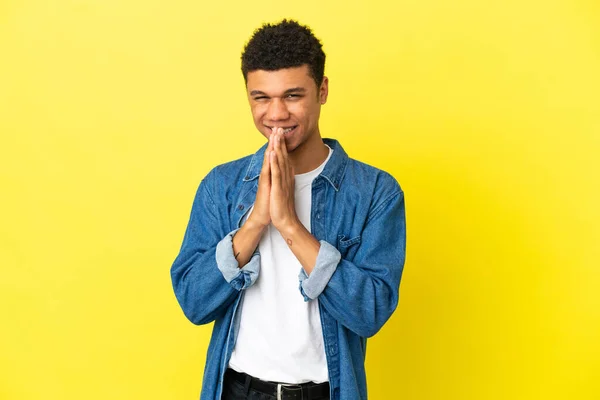 Jovem Afro Americano Isolado Fundo Amarelo Mantém Palma Mão Unida — Fotografia de Stock