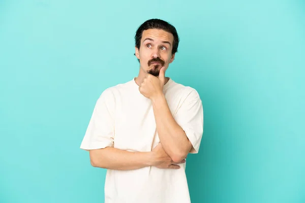 Joven Hombre Caucásico Aislado Sobre Fondo Azul Teniendo Dudas — Foto de Stock