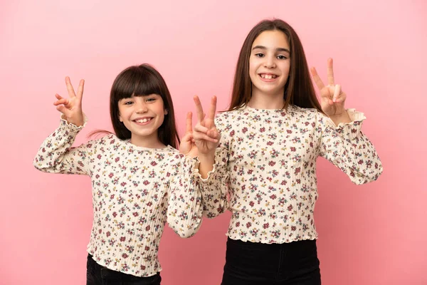 Hermanitas Niñas Aisladas Sobre Fondo Rosa Sonriendo Mostrando Signo Victoria —  Fotos de Stock