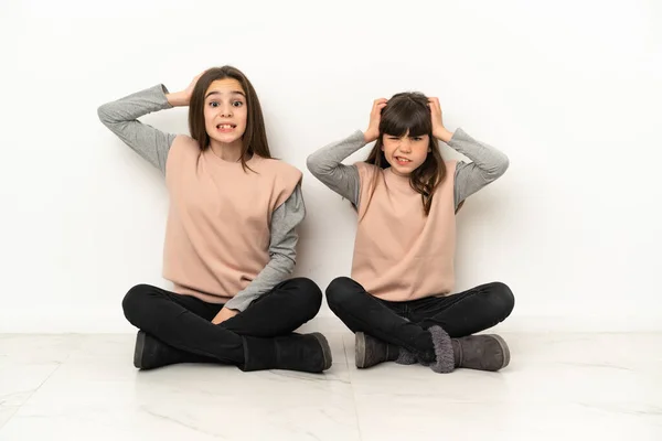 Irmãzinhas Sentadas Chão Isoladas Fundo Branco Dão Mãos Cabeça Porque — Fotografia de Stock