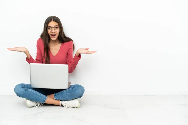 年轻的法国姑娘坐在地板上 手里拿着笔记本电脑 脸上带着震惊的表情 — 图库照片