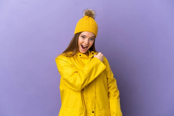 Chica Adolescente Con Abrigo Impermeable Sobre Fondo Púrpura Aislado Celebrando —  Fotos de Stock