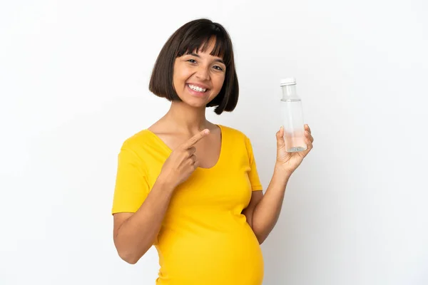 白い背景に隔離された水のボトルを持っている若い妊婦は 製品を提示する側を指しています — ストック写真