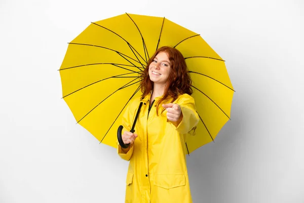 十代の若いですRedhead女の子レインプルーフコートと傘隔離上の白い背景ポインティングフロントで幸せな式 — ストック写真