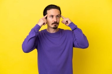 Sarı arka planda soyutlanmış genç beyaz bir adamın şüpheleri ve düşünceleri var.