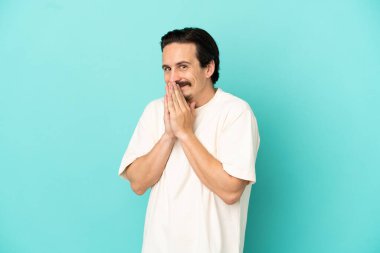 Mavi arka planda izole edilmiş genç beyaz adam avuç içlerini bir arada tutuyor. İnsan bir şey ister.