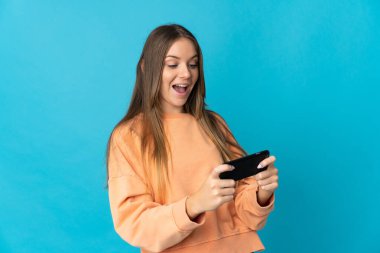 Young Lithuanian woman isolated on blue background playing with the mobile phone